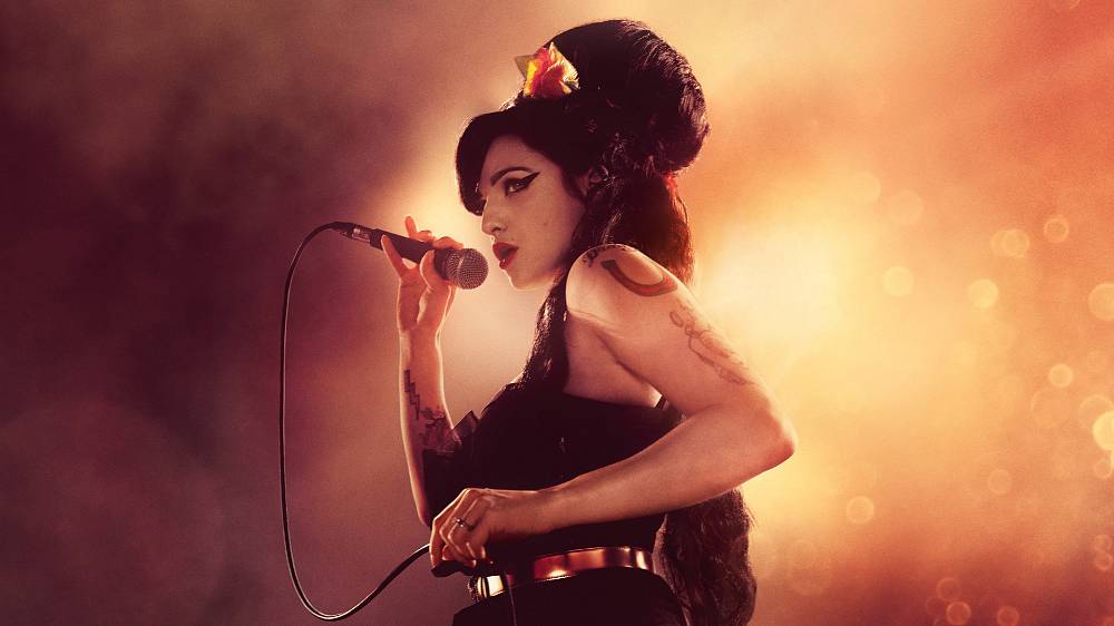 Back to Black (2024).
Dva lidé měli zásadní vliv na život a kariéru Amy Winehouse. Tím prvním byla její babička Cynthia, svérázná, oduševnělá a originální žena, která jí předala svou živočišnost, lásku k jazzu, touhu jít vždycky vlastní cestou a nedělat na ní kompromisy. Tím druhým člověkem byl její přítel Blake. Život s ním připomínal jízdu na hodně zběsilé horské dráze, během níž si Amy osvojila pár nepříjemných závislostí. Paradoxně v nejsložitějším období svého života, v době, kdy o oba tyhle opěrné body přišla (babička zemřela na rakovinu plic a s Blakem se rozešla), vznikla její zásadní deska „Back to Black“, která patří k tomu nejlepšímu, co v hudbě 21. století prozatím vzniklo. Amy se díky ní stala superhvězdou, dala se znovu dohromady s Blakem, ale pozornost celého světa, které se ji dostávalo, neměla tahle možná až příliš křehká holka šanci ustát, i když se o to snažila a málem se jí to podařilo.